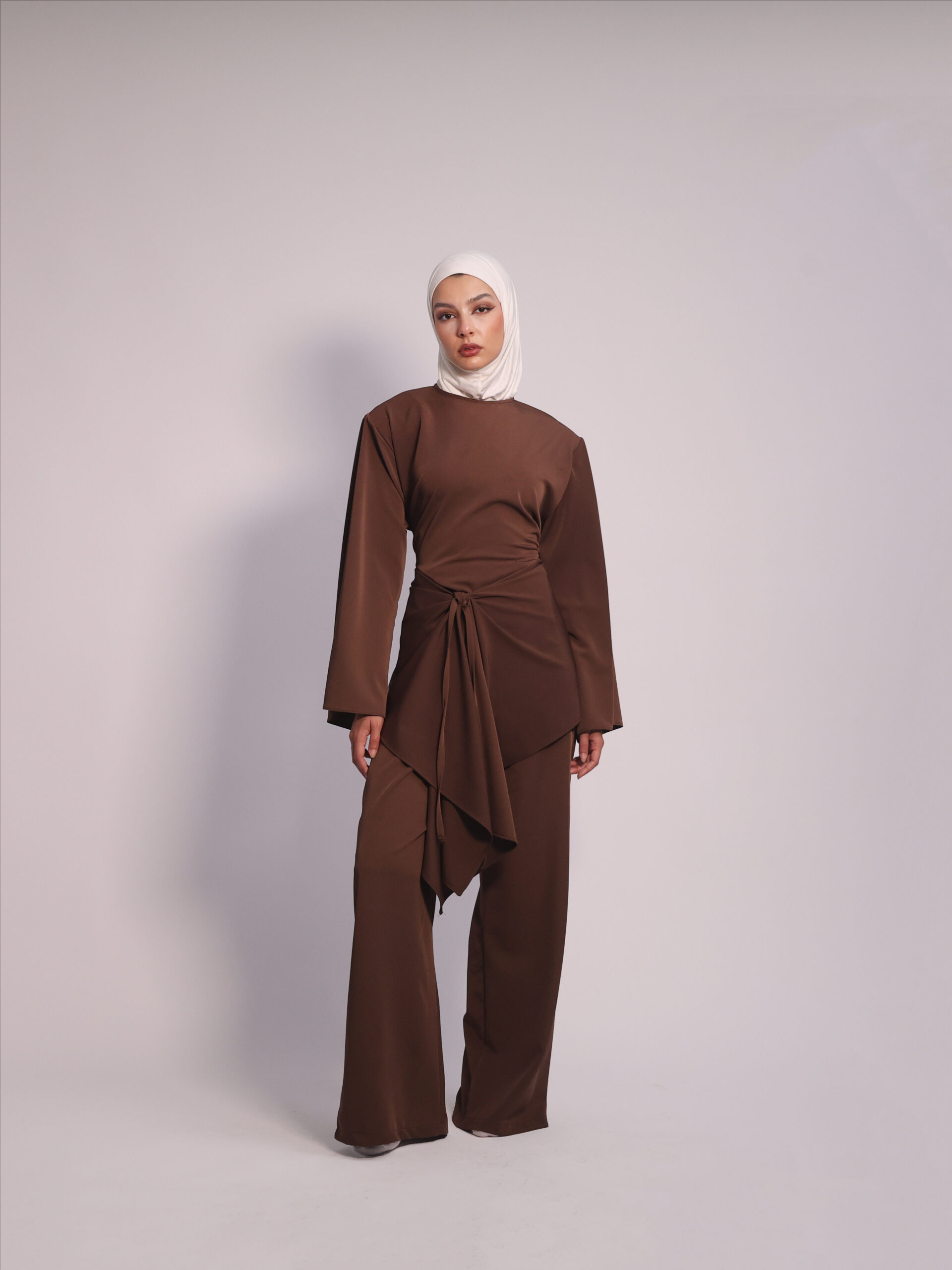 Draped Waist 3-Piece Set in Brown by Kharzaat featuring a long-sleeve top, wide-leg pants, and removable draped waist piece